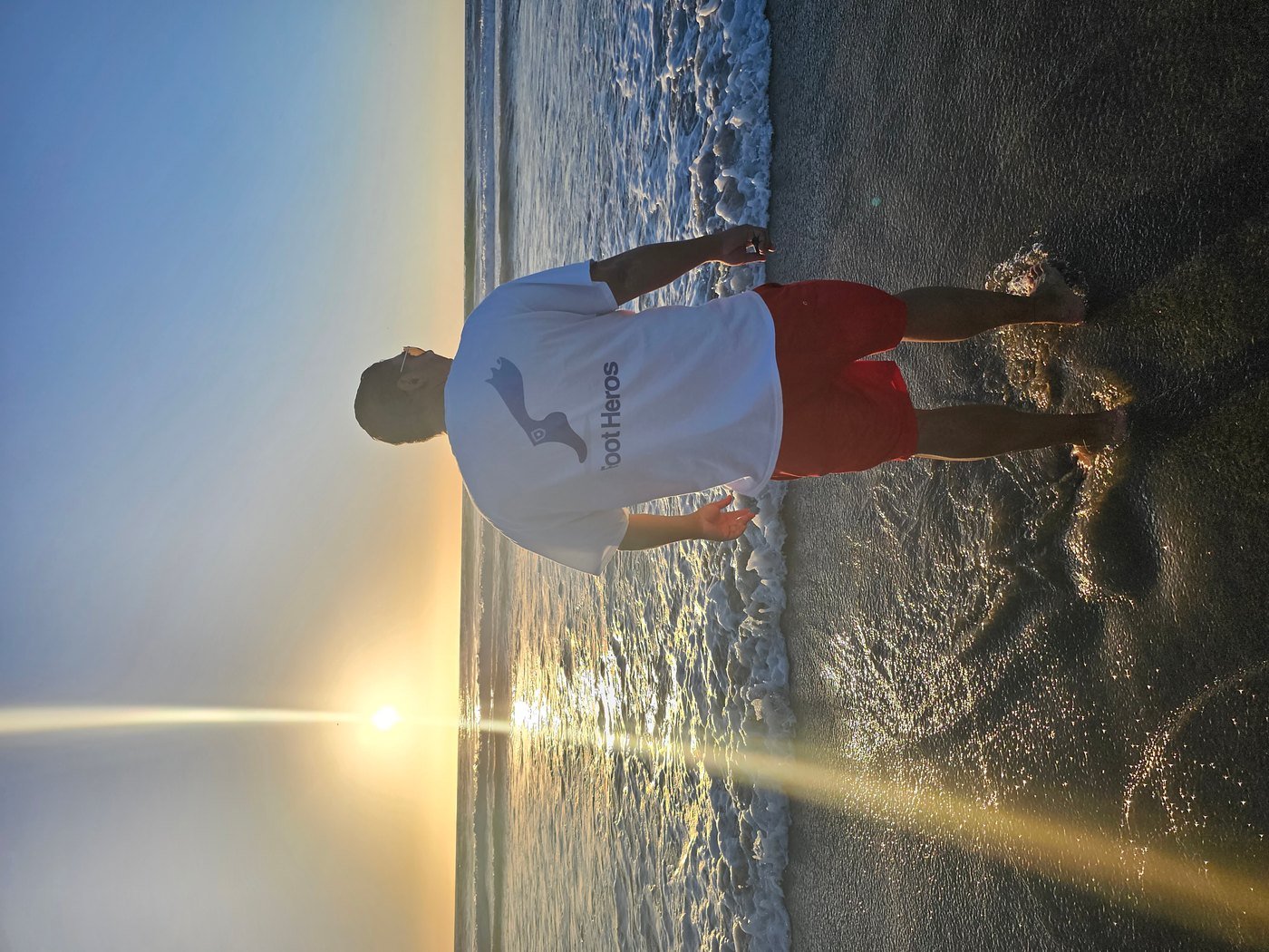 The founder standing at the shoreline wearing a Foot Heros shirt